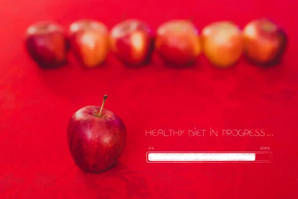 group of red apples on table cloth of the same color with text healthy diet in progress