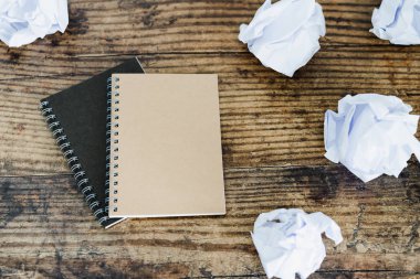 bloknot ve nötr tonlar ile koyu ahşap yüzeyde buruşuk Kağıt topları ile minimalist Resepsiyon ayarı flatlay