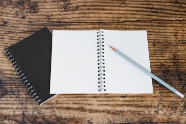 minimalist desk setting flatlay with opened ruled notepad and pencil on dark wooden surface with neutral tones