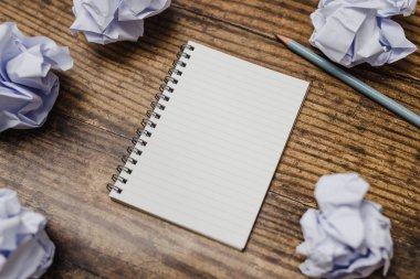 Not defteri ve kalem buruşuk Kağıt topları nötr tonları ile koyu ahşap yüzeyde çevrili minimalist Resepsiyon flatlay ile açılan ayarlama karar verdi