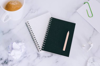 mini spiral defter kalem ile flatlay ve kahve mermer masa üzerinde yukarıdan aşağıya doğru perspektif vurdu
