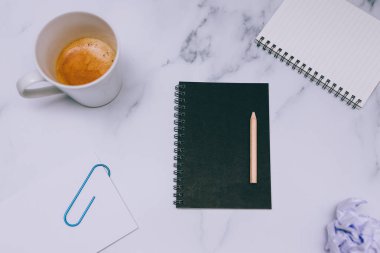 mini spiral defter kalem ile flatlay ve kahve mermer masa üzerinde yukarıdan aşağıya doğru perspektif vurdu