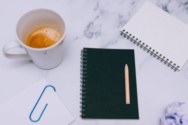 mini spiral defter kalem ile flatlay ve kahve mermer masa üzerinde yukarıdan aşağıya doğru perspektif vurdu