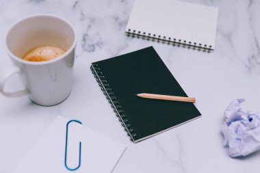 mini spiral defter kalem ile flatlay ve kahve mermer masa üzerinde yukarıdan aşağıya doğru perspektif vurdu
