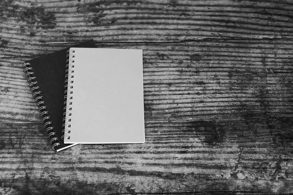 minimalist desk setting flatlay with notepads on dark wooden surface in black and white
