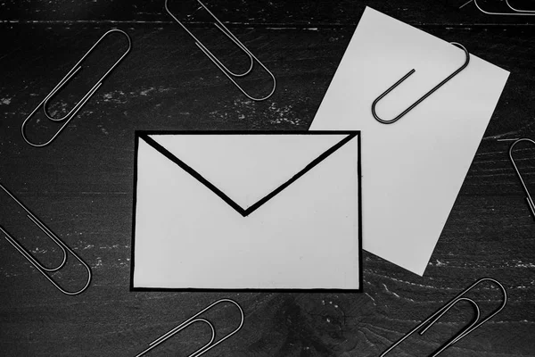 funny metaphor of inbox with email envelop and attachment clip on real-life desk, flatlay shot from topdown perspective