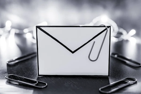 envelope with clip symbol of email and attachments with fairy light bokeh in the background shot at shallow depth of field