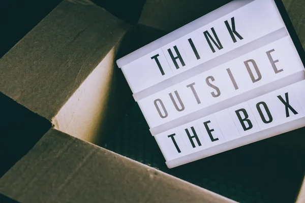 Think outside the box message on lightbox coming out of a parcel, concept of being unique for success