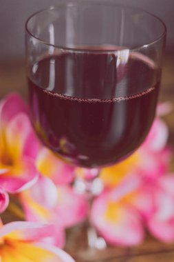 yakın çekim cam yoğun renkli kırmızı şarap ve ahşap masa, zarif ya da pahalı şarap seçimler kavramı üzerinde Avustralya tropik çiçekler