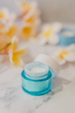 Spa ve cilt bakım tedavileri kavramı, nemlendirici ve bodur tencere egzotik frangipani çiçekler ile mermer masa