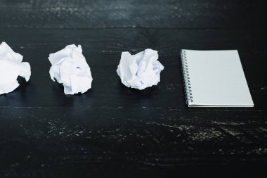 belgeler hazırlanması ve bir metin yazmak için mücadele kavramı ayarla boş not defteri ve buruşuk Kağıt topları karanlık moody arka plan üzerinde