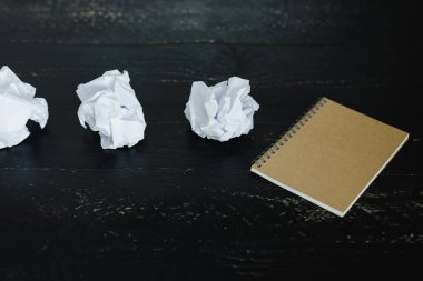 belgeler hazırlanması ve bir metin yazmak için mücadele kavramı ayarla boş not defteri ve buruşuk Kağıt topları karanlık moody arka plan üzerinde