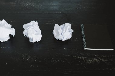 belgeler hazırlanması ve bir metin yazmak için mücadele kavramı ayarla boş not defteri ve buruşuk Kağıt topları karanlık moody arka plan üzerinde