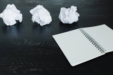 belgeler hazırlanması ve bir metin yazmak için mücadele kavramı ayarla boş not defteri ve buruşuk Kağıt topları karanlık moody arka plan üzerinde