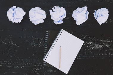 belgeler hazırlanması ve bir metin yazmak için mücadele kavramı ayarla boş not defteri ve buruşuk Kağıt topları karanlık moody arka plan üzerinde