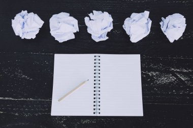 belgeler hazırlanması ve bir metin yazmak için mücadele kavramı ayarla boş not defteri ve buruşuk Kağıt topları karanlık moody arka plan üzerinde