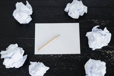 belgeler hazırlanması ve bir metin yazmak için mücadele kavramı ayarla boş not defteri ve buruşuk Kağıt topları karanlık moody arka plan üzerinde