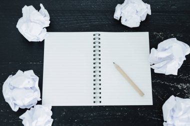 belgeler hazırlanması ve bir metin yazmak için mücadele kavramı ayarla boş not defteri ve buruşuk Kağıt topları karanlık moody arka plan üzerinde