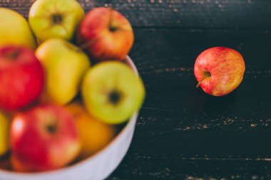 Grup koyu ahşap arka plan, organik ürünler ve plentiness kavramı üzerinde beyaz bir kase karışık kırmızı yeşil ve Sarı elmalar