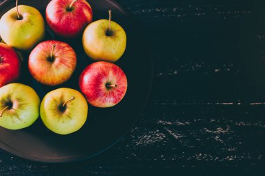Organik grup siyah arka plan, en iyi ürün ve sağlıklı gıda seçme kavramı üzerine karanlık plaka üzerinde kırmızı elma yeşil ve sarı renkler karışık