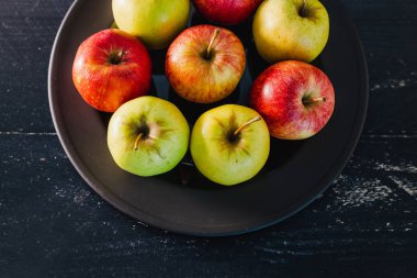 Organik grup siyah arka plan, en iyi ürün ve sağlıklı gıda seçme kavramı üzerine karanlık plaka üzerinde kırmızı elma yeşil ve sarı renkler karışık