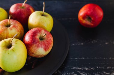 Organik grup siyah arka plan, en iyi ürün ve sağlıklı gıda seçme kavramı üzerine karanlık plaka üzerinde kırmızı elma yeşil ve sarı renkler karışık