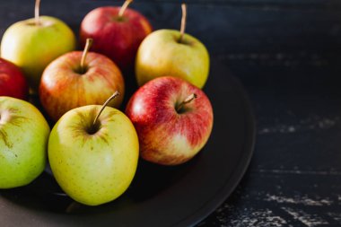 Organik grup siyah arka plan, en iyi ürün ve sağlıklı gıda seçme kavramı üzerine karanlık plaka üzerinde kırmızı elma yeşil ve sarı renkler karışık