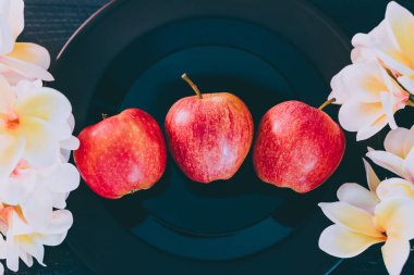 elma siyah plaka en iyi organik ürünler seçme kavramı koyu arka plan ve çevrelerindeki beyaz çiçekler