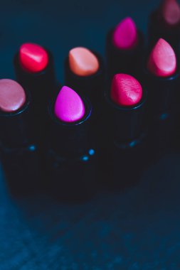 pembe ve çıplak kırmızı rujları farklı renkler ve dokular karanlık tablo, alan sığ derinliği ile ateş yakın çekim grup