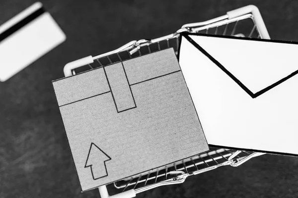 送料とあなたのオンライン配達の追跡の概念の具体的机の上段ボール小包メール封筒とお支払いカードとショッピング カート — ストック写真
