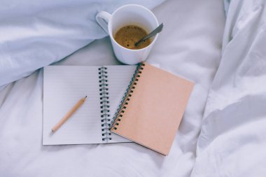 boş boşaltmak ile bloknot ve yatakta kupa kahve yanında, kavram sabah başlayan ve bir zamanlama yazma veya yapılacaklar listesi ile kalem