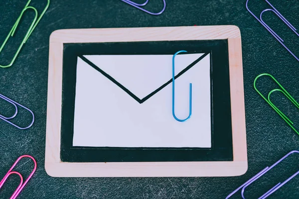 email envelope on blackboard with paper clip symbol of attachment, metaphor of internet communication