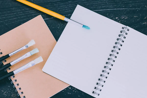 Escritorio con bloc de notas y pinceles de acuarela con páginas vacías y — Foto de Stock