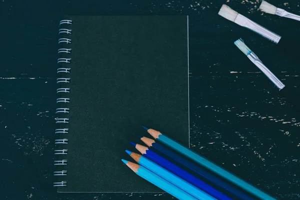 Bureau noir avec bloc-notes noir et crayons de couleur avec aquarelle — Photo