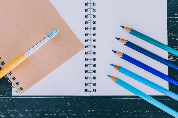 Scrivania con blocco appunti e pennello ad acquerello e matite colorate wi — Foto Stock