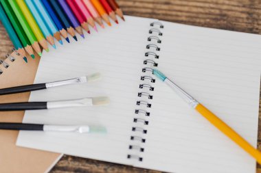 defter ile fırçalar ve renkli kalemler ahşap masa