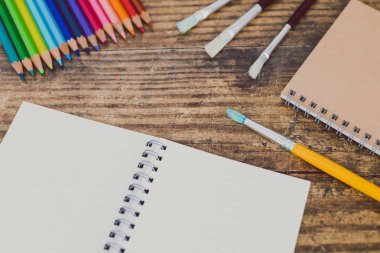 defter ile fırçalar ve renkli kalemler ahşap masa