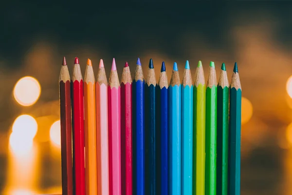used color pencils lined up with fairy lights bokeh in the backg