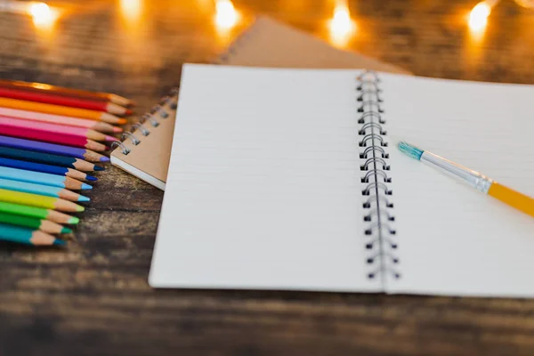 Notebook s kartáčky a barevné tužky na dřevěný stůl s fair — Stock fotografie
