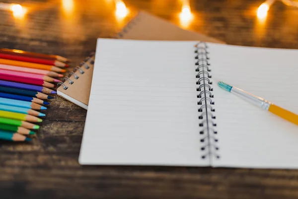 Notebook s kartáčky a barevné tužky na dřevěný stůl s fair — Stock fotografie