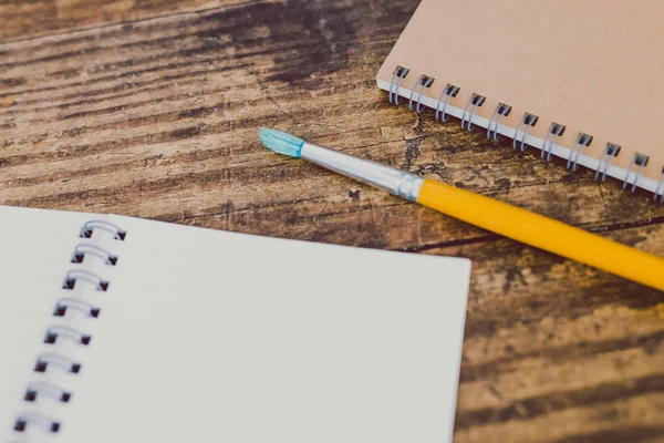 Cuadernos con pincel sobre escritorio de madera —  Fotos de Stock