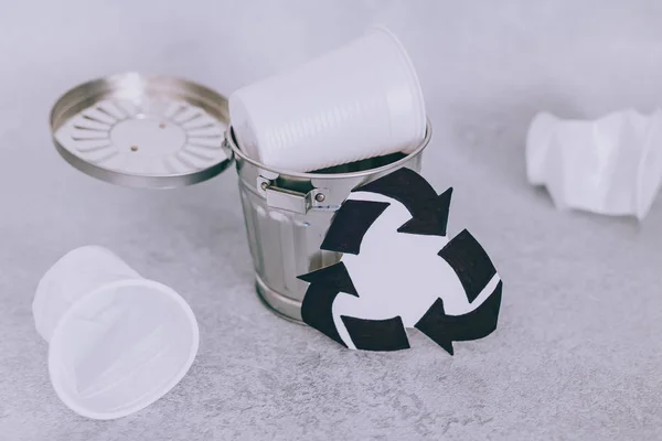 Одноразовые чашки и мусорный бак с символом переработки, концепция — стоковое фото