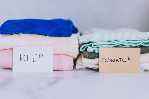 Piles of tshirts and clothes being sorted into Keep Discard and — Stock Photo, Image