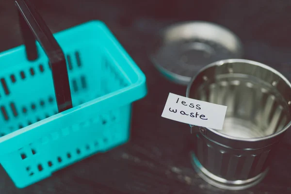 Spend better for less waste shopping basket next to gargabe bin — Stock Photo, Image