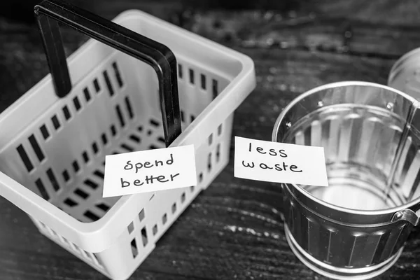 Spend better for less waste shopping basket next to gargabe bin — Stock Photo, Image