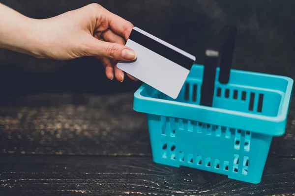 hand holding payment card with shopping basket next to it