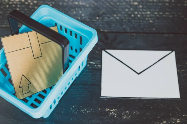 shopping basket with parcel inside and email envelope next to it