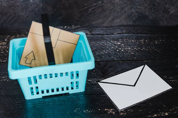 shopping basket with parcel inside and email envelope next to it