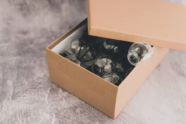 Caja abierta con bombilla en miniatura que sale de ella — Foto de Stock