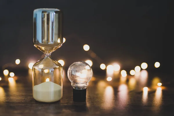 Time for new ideas hourglass and lightbulb surrounded by fairy l — Stock Photo, Image